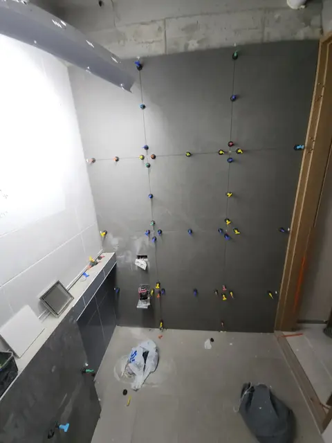 욕실 벽타일 시공 중 레벨링 클립으로 면을 맞추는 모습